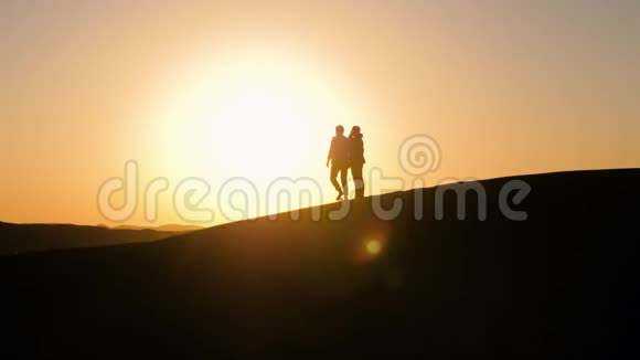 两个人在沙漠中日落的剪影视频的预览图