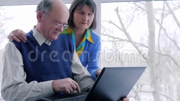 网络娱乐拥有笔记本电脑的老夫妇休闲度假视频的预览图