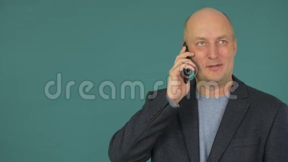 秃顶的中年商人微笑着在智能手机上交谈在找摄像机视频的预览图