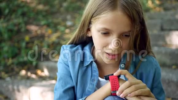儿童在智能手表交谈儿童使用智能手表女孩户外公园视频的预览图