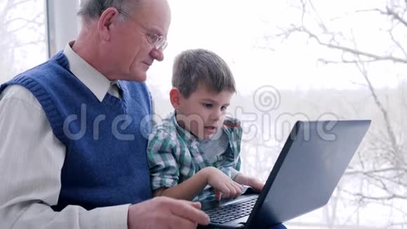 通过笔记本电脑在线购物男孩和祖父在互联网上选择商品视频的预览图