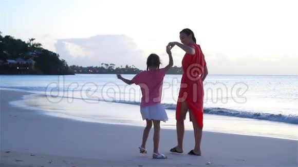 美丽的母亲和女儿在加勒比海海滩享受日落乐趣家人在海滩度假流动人口视频的预览图