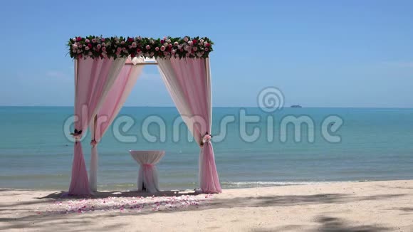 海边沙滩上可循环观看的粉色婚礼拱门视频的预览图