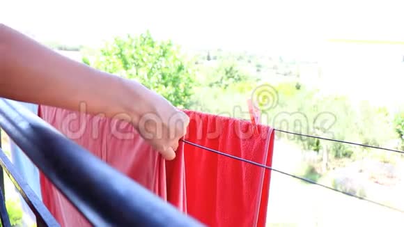女人在阳台上挂毛巾和床单晾干女性的手把洗涤钉在线上洗衣服慢点视频的预览图