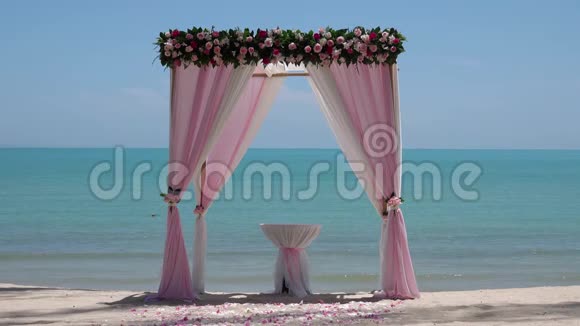 海边沙滩上可循环观看的粉色婚礼拱门视频的预览图