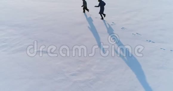 妈妈和太阳在雪地里一起奔跑空中镜头冬天的家庭消遣视频的预览图