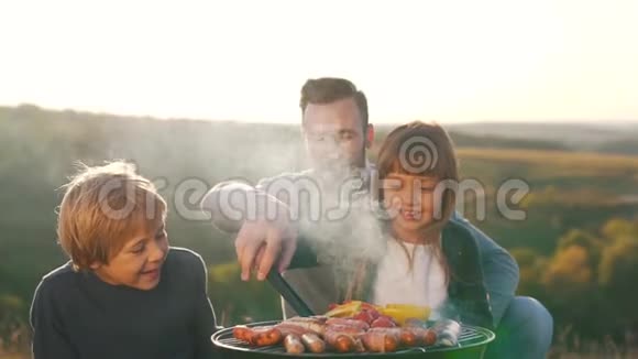 父亲带着孩子在烤架上煮香肠视频的预览图