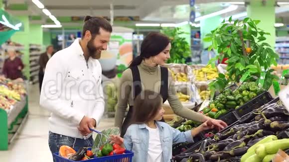 年轻快乐的父母带着孩子在超市买蔬菜视频的预览图