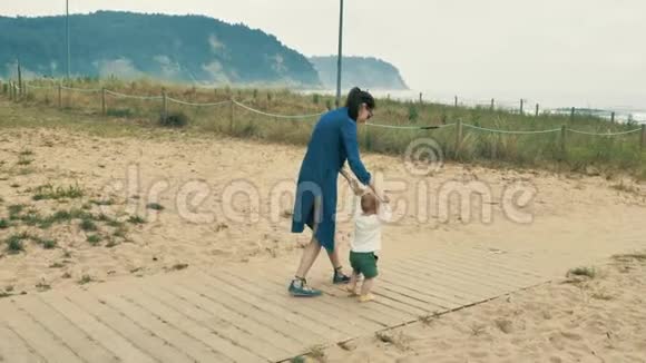4K漂亮的小女孩妈妈在坎塔布里亚海岸和她可爱的小宝宝散步和玩耍视频的预览图
