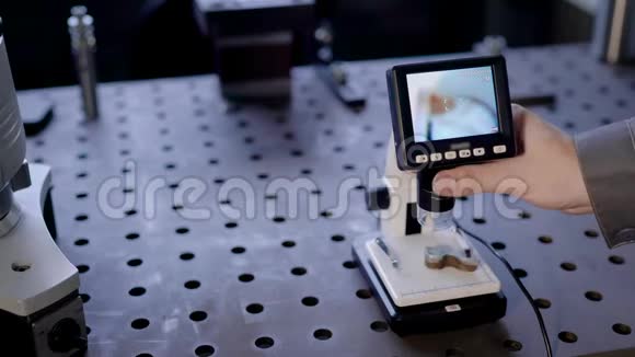 实验室助理正在实验室里检查一个金属部件用数字显微镜观察显示器视频的预览图