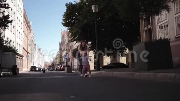 年轻快乐的妈妈在街上追赶一个小女孩视频的预览图