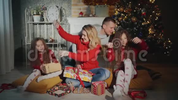 幸福的四口之家正微笑着在圣诞树下为新年之夜做准备视频的预览图