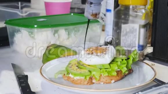 健康的早餐用煎蛋和鳄梨做三明治把酱汁倒进去视频的预览图
