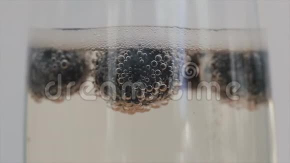 香槟泡沫的特写附着在蓝莓上漂浮在玻璃中视频的预览图