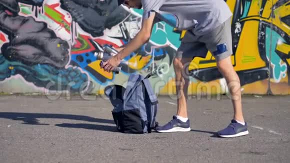 一个年轻人正把装有油漆的气雾桶放进背包里视频的预览图