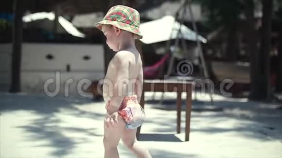 戴帽子的快乐男孩沿着沙滩散步视频的预览图