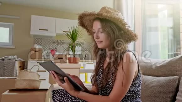女人用平板电脑后面有盒子新房子里带手机的年轻美女画像视频的预览图