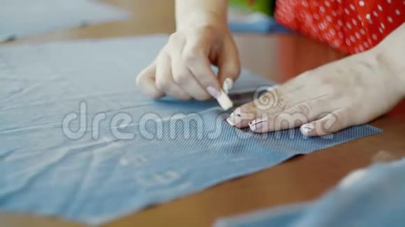 在她的店里工作的一位女裁缝的手上贴紧在布料上画模板视频的预览图