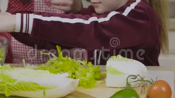 带着妈妈的小女孩撕了一个豌豆沙拉放进碗里视频的预览图