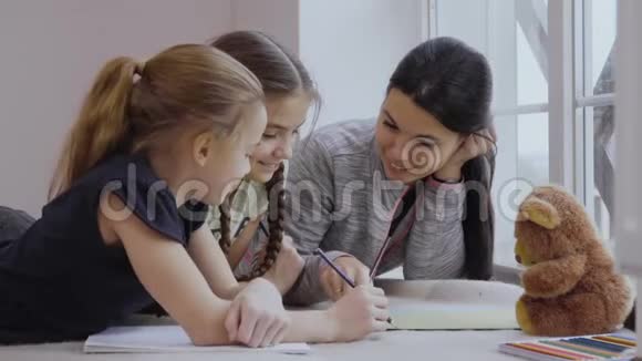 两个可爱的女孩和他们的母亲在家里画着一幅轻松的图画视频的预览图