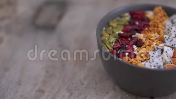 用木瓜火龙果麦片樱桃干和南瓜子做成的冰沙碗的特写镜头健康早餐视频的预览图