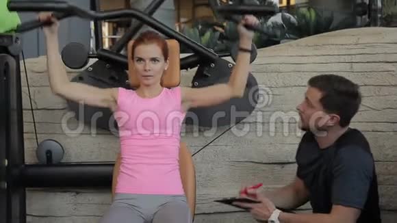 女运动员正在训练手臂她的私人男教练正在观察锻炼视频的预览图