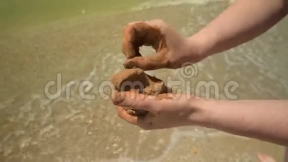 特写双手在沙滩上做粘土沙滩和海浪为背景夏天和旅行的概念视频的预览图