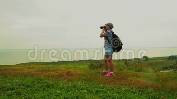 一位背着背包的女游客在山上拍了一张湖的照片视频的预览图
