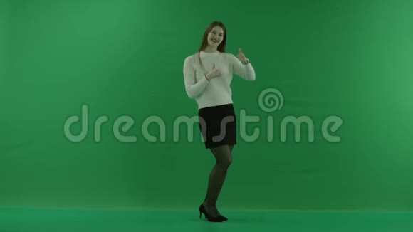 女孩站在半个转弯处看着右边竖起大拇指对着镜头在绿色的屏幕上跳舞视频的预览图