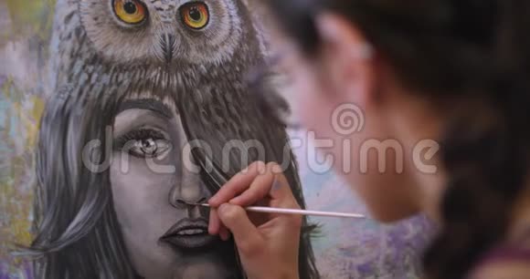 女艺术家画了一幅萨满画从后面滑过来艺术家在画布上用丙烯酸颜料作画视频的预览图