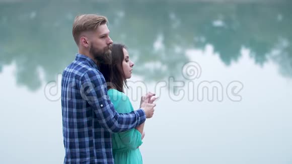 绿松石湖背景下的一对年轻夫妇视频的预览图