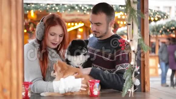 在圣诞节的时候有一对年轻的夫妇在外面玩他们正在喝酒喝着酒抱着可爱的狗圣诞节视频的预览图