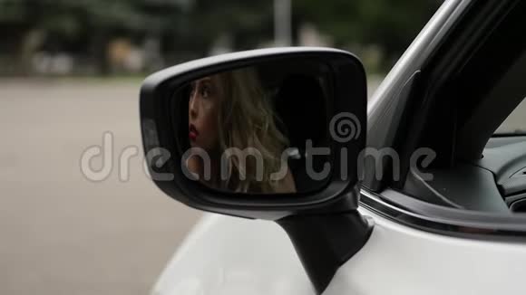 一位身材魁梧的金发女人坐在汽车的方向盘上看着汽车侧面的镜子慢动作视频的预览图
