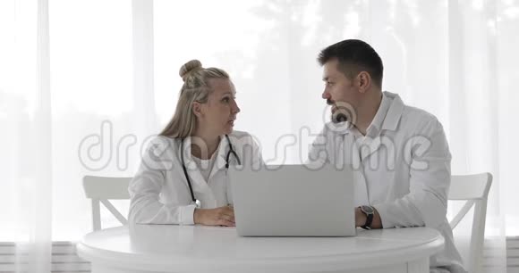 两个医生一起用笔记本电脑在他们的办公室里谈论一个病人视频的预览图