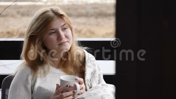 舒适的家居概念年轻女子坐在格子呢的开放式露台上享受热咖啡4千克视频的预览图