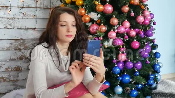 圣诞节概念年轻女子在装饰圣诞树附近自拍照片视频的预览图