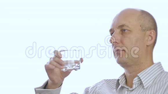 肖像秃顶男子从白色背景的玻璃中饮水视频的预览图