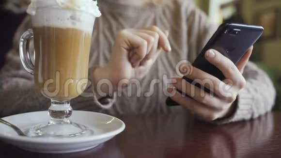 女人在智能手机上使用应用程序在咖啡馆喝咖啡在手机上发短信视频的预览图