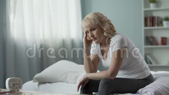 暂停期成年女性坐在床上患有偏头痛健康视频的预览图