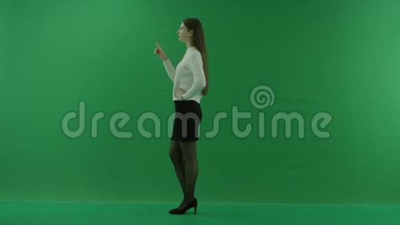 年轻女子站在她的左边滚动屏幕在绿色屏幕上思考一些事情视频的预览图