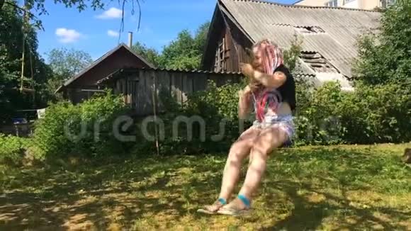 快乐的女孩在乡村花园的谷仓里摇摆慢动作视频的预览图