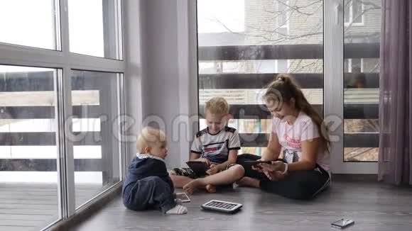 现代童年概念4个孩子坐在一起房间的地板上放着手机和平板电脑窗户是全景视频的预览图