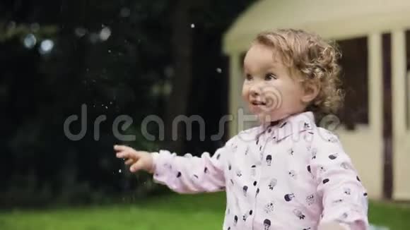 小卷曲的女孩在巨大的泡沫中感到快乐慢动作泡泡秀视频的预览图