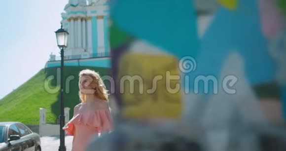 快乐迷人的年轻女孩卷曲的金发和自然的化妆走在阳光明媚的街道上4K录像视频的预览图