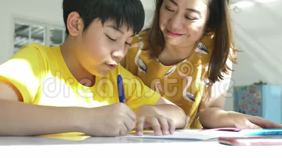 慢动作的亚洲妈妈和儿子在家做作业带着笑脸视频的预览图
