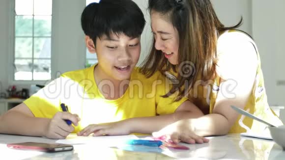 慢动作的亚洲妈妈和儿子在家做作业带着笑脸视频的预览图