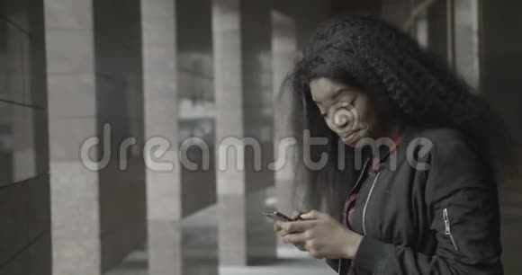 迷人的快乐年轻的非洲女孩在发短信聊天和通过手机浏览时笑着笑着视频的预览图