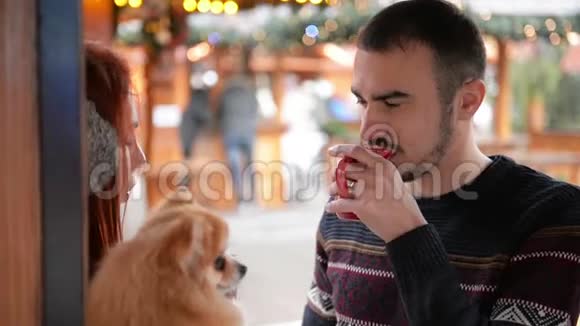 在圣诞节的时候有一对年轻的夫妇在外面玩他们正在喝酒喝着酒抱着可爱的狗视频的预览图