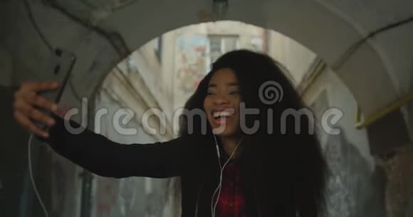 一个快乐迷人的非洲女孩的情感肖像她的卷发通过手机自拍视频的预览图