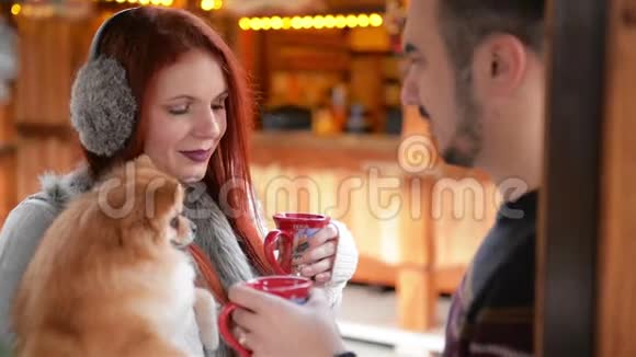 在圣诞节的时候有一对年轻的夫妇在外面玩他们正在喝酒喝着酒抱着可爱的狗视频的预览图